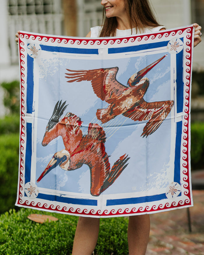 Person holding a square scarf with pelican design outdoors