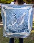 Person holding a decorative fabric with quail design outdoors