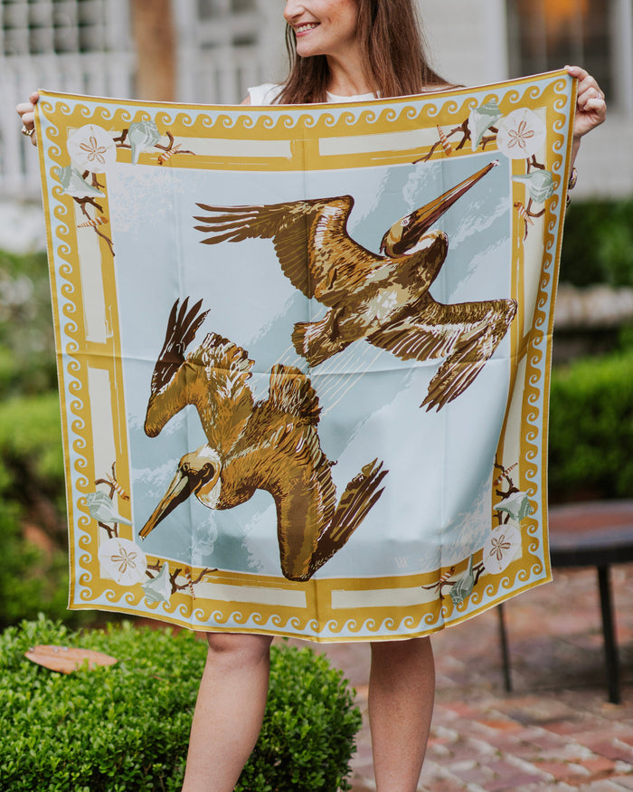 Person holding a large scarf with pelican design outdoors