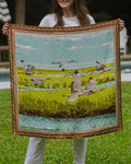 Woman holding a silk scarf with birds flying over a marsh and a decorative border.
