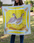 Person holding a large silk scarf with a quail and pinecone design outdoors