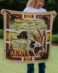 A woman holds up a square silk scarf featuring a German Shorthaired Pointer dog in a marsh with ducks and birds.