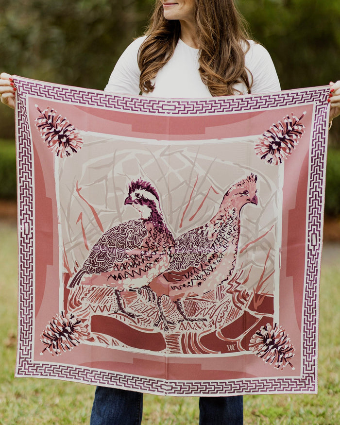 Person holding a large pink scarf with bird design outdoors