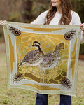 Person holding a decorative scarf with quail and pine cone design outdoors