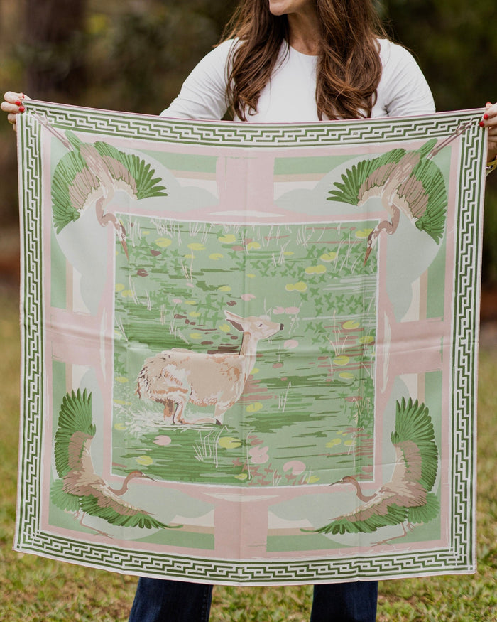 Person holding a large decorative scarf with deer design outdoors