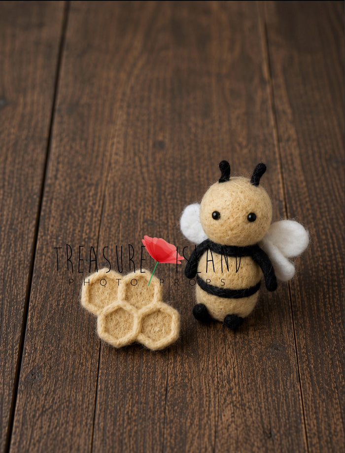 Handmade felted bee photography prop with tiny felt honeycomb detail, styled on vintage rustic wooden floor background.