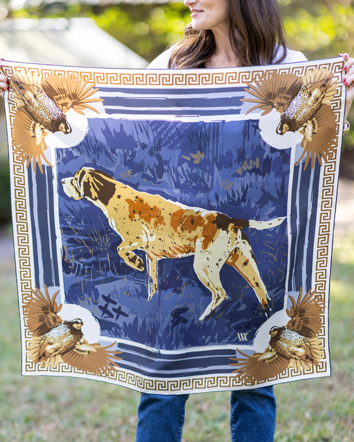 Person holding a large scarf with a hunting scene design featuring a dog and birds.