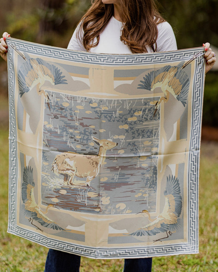 Person holding a decorative scarf with deer design outdoors