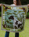 A woman holding up a square silk scarf. The scarf features a hunting dog in a pond with lily pads, birds, and a decorative border.