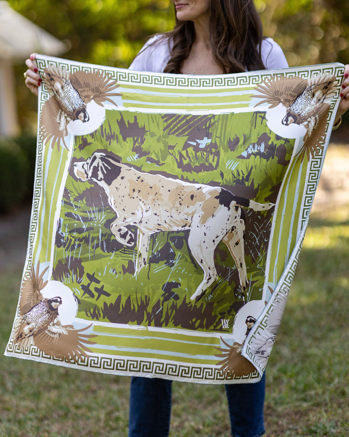 Person holding a silk scarf with a dog and bird design outdoors