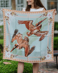Person holding a square scarf with pelican design outdoors