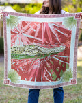Person holding a decorative towel with a pink and green design outdoors
