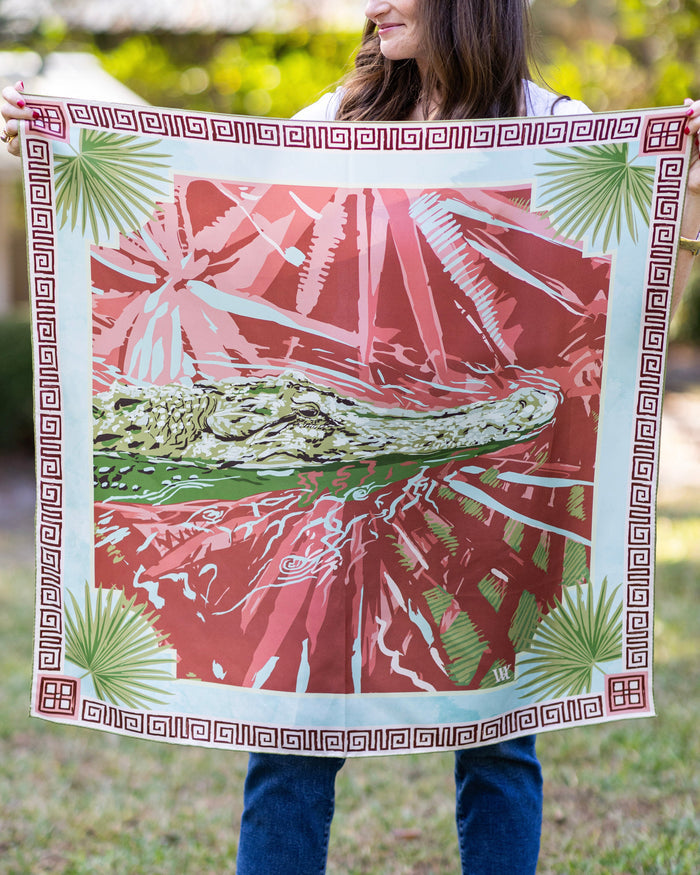 Person holding a decorative towel with a pink and green design outdoors