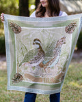 Person holding a large silk scarf with quail and pine cone  design outdoors