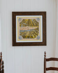 A framed art print featuring a stylized illustration of a alligator in a yellow and green patterned background, hanging on a white paneled wall above a wooden dining table and chairs.