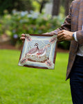 A man holding a pocket square. The silk pocket square features a detailed illustration of a quail in a natural setting with pinecone accents.