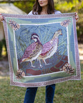 Person holding a large silk scarf with a design of two quail and pinecones.