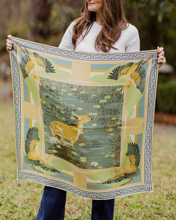 Person holding a silk scarf with scenic deer design outdoors