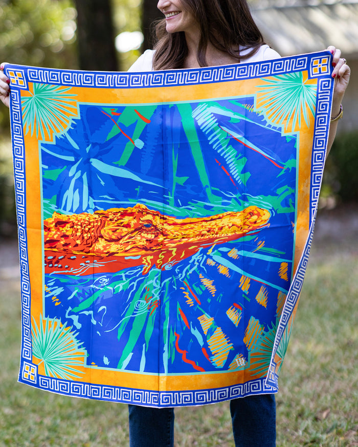 Person holding a colorful scarf with an alligator design outdoors