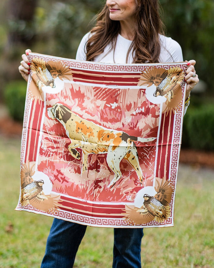 woman holding a wine colored silk scarf with a bird dog and quail design